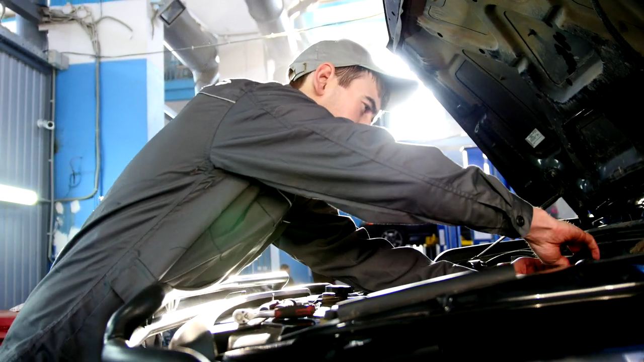 A mechanic working under the hood of a car
