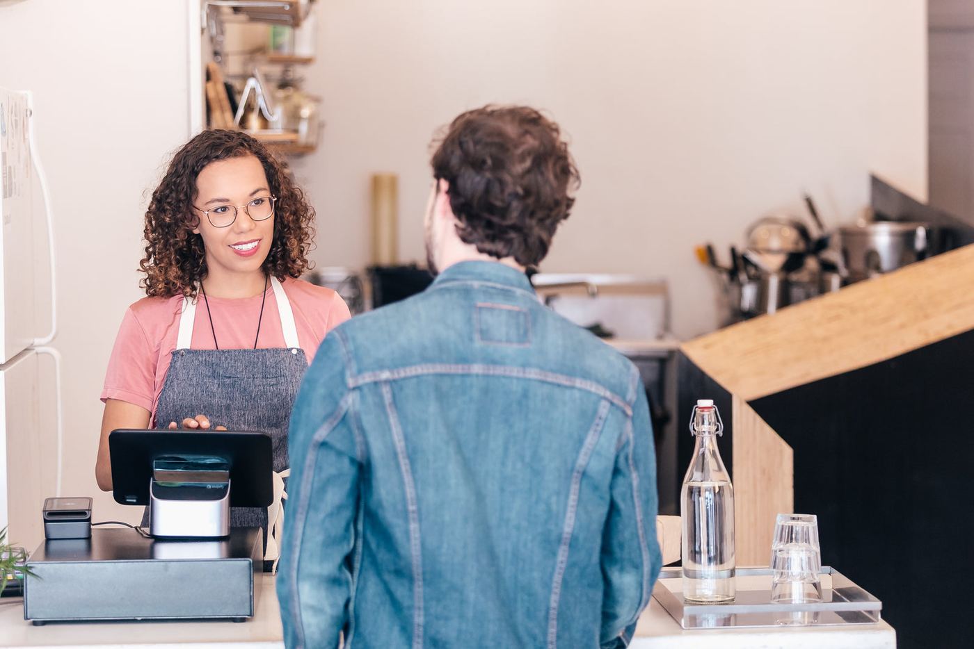 A café owner chatting with a customer at the till