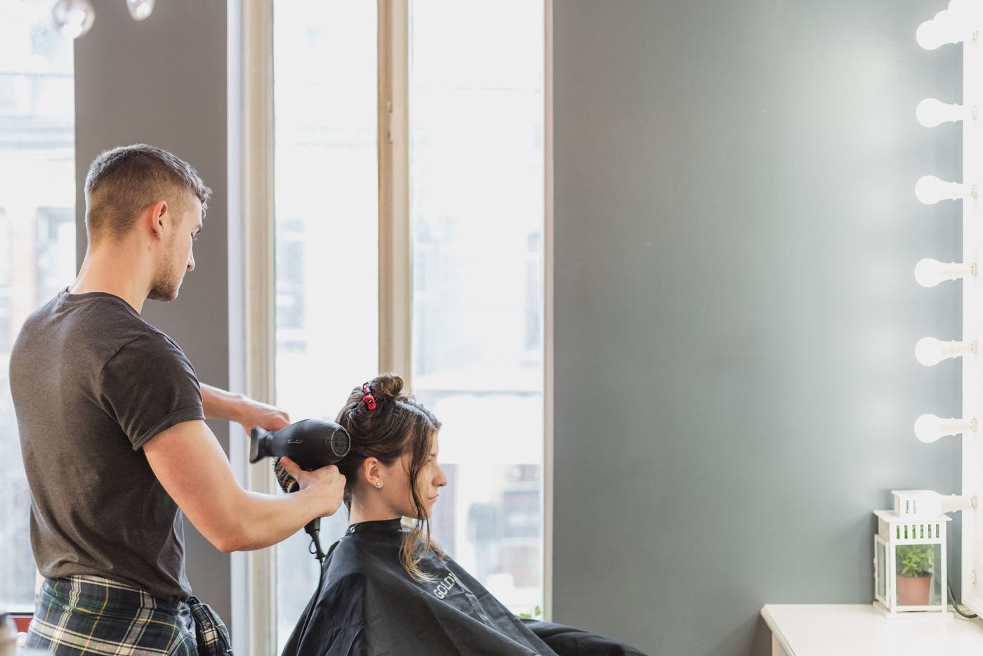 A stylist blow-drying a client's hair in a bright salon