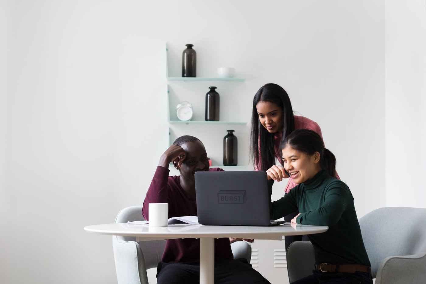Three coworkers looking at a laptop together